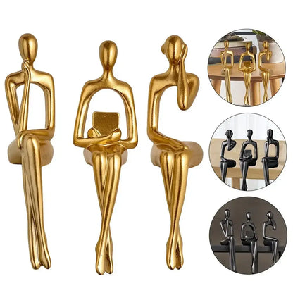 Set of three gold decorative statues on a white background