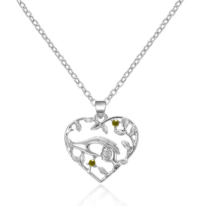 Silver heart-shaped pendant with green stones on a white background