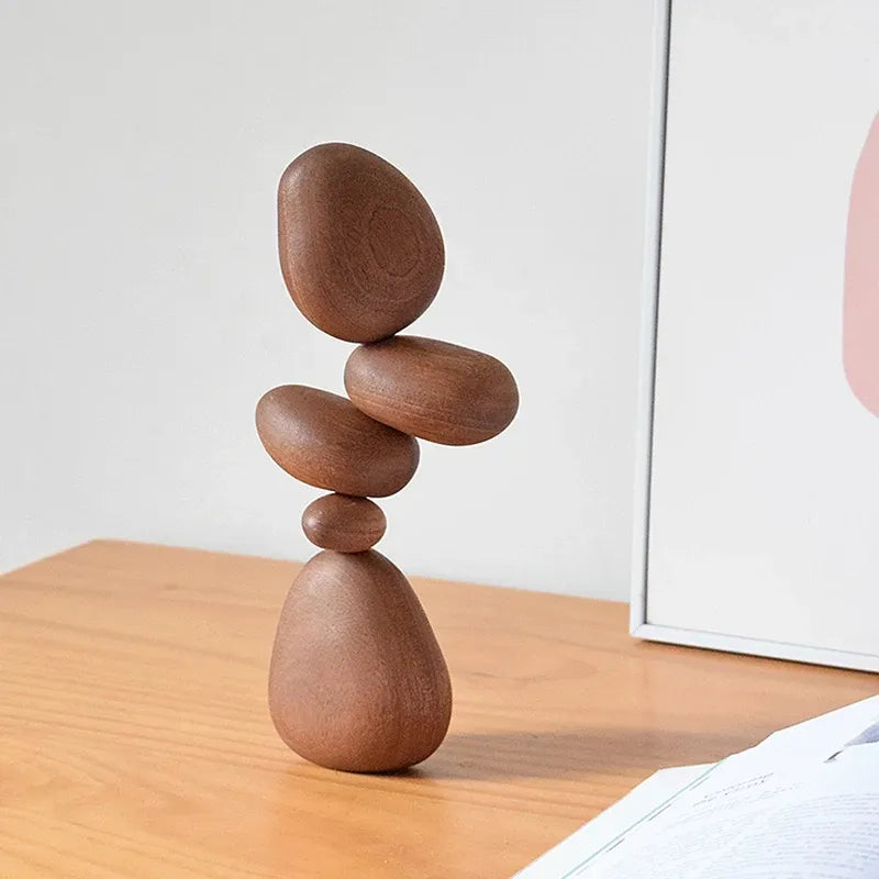 Stack of wooden stones balanced on a wooden surface with a white wall in the background