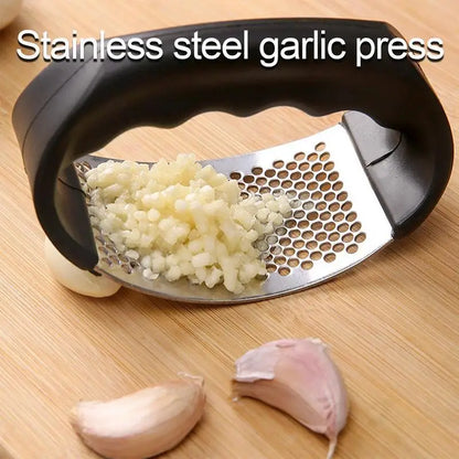 Stainless steel garlic press with minced garlic on a wooden surface