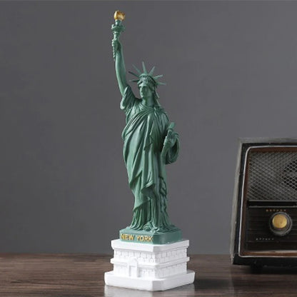 Statue of Liberty model on a wooden surface with a vintage radio in the background