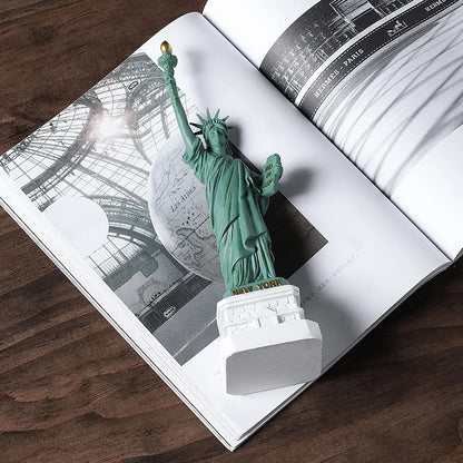 Statue of Liberty model on an open book with architectural illustrations