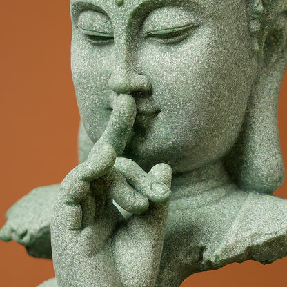 Statue of a Zen Buddhist with a finger on the lips against an orange background