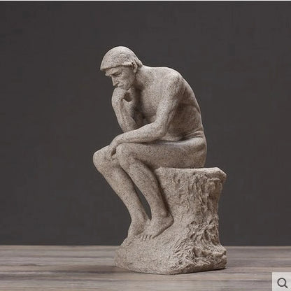 Statue of a thinker sitting on a pedestal against a dark background