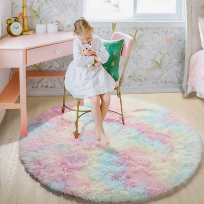 Child sitting on a colorful round rug in a room with a desk and chair.