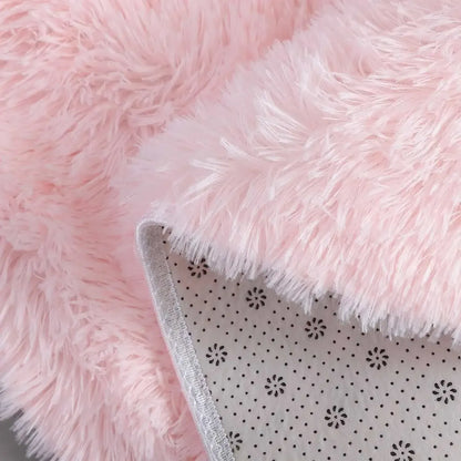 Close-up of a pink fluffy blanket with a corner showing a polka dot pattern.