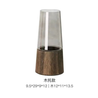 Tall cylindrical vase with wooden base and transparent glass top on a white background
