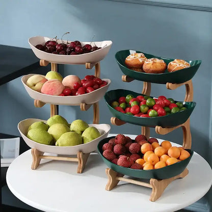 Three-tiered fruit and dessert stand with various fruits and pastries on a white surface.