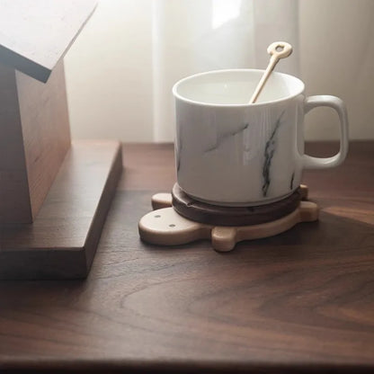White mug with black design on a wooden coaster on a wooden surface