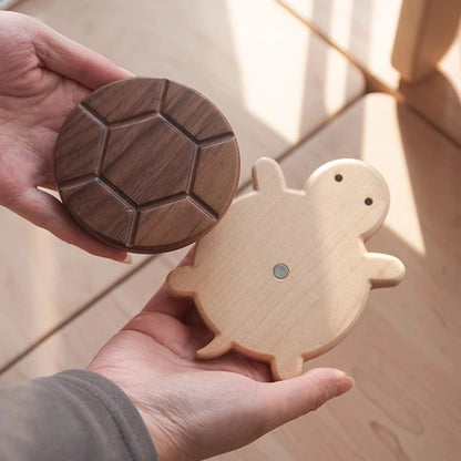 Wooden turtle toy and geometric wooden disc held in hands against a wooden background