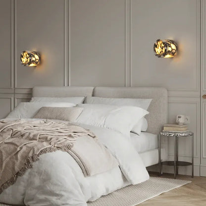 Two wall-mounted lights and a beige blanket in a bedroom setting.