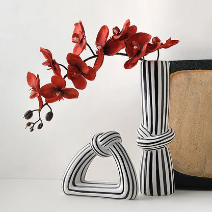 Two black and white patterned vases with a red flower arrangement on a light background