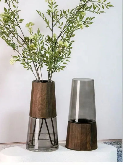 Two decorative vases with wooden bases and glass bodies on a white surface.