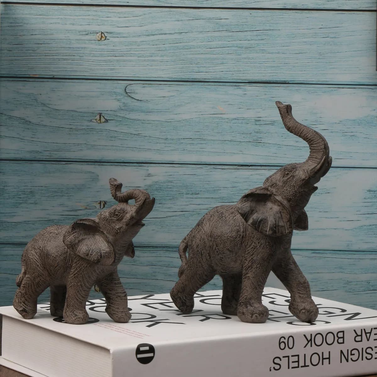 Two elephant figurines on a box with a blue wooden background
