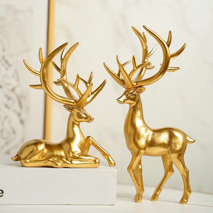 Two gold deer figurines on a white surface with a light gray background