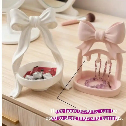 Two jewelry organizers with bow designs on a wooden surface.