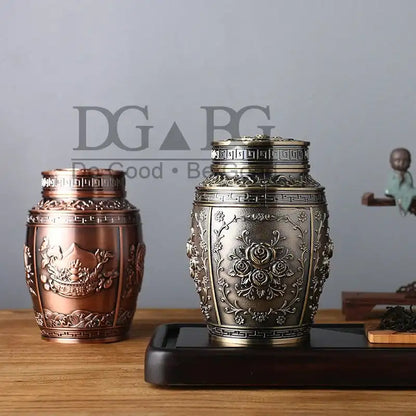 Two ornate metal urns on a wooden surface with a blurred background.