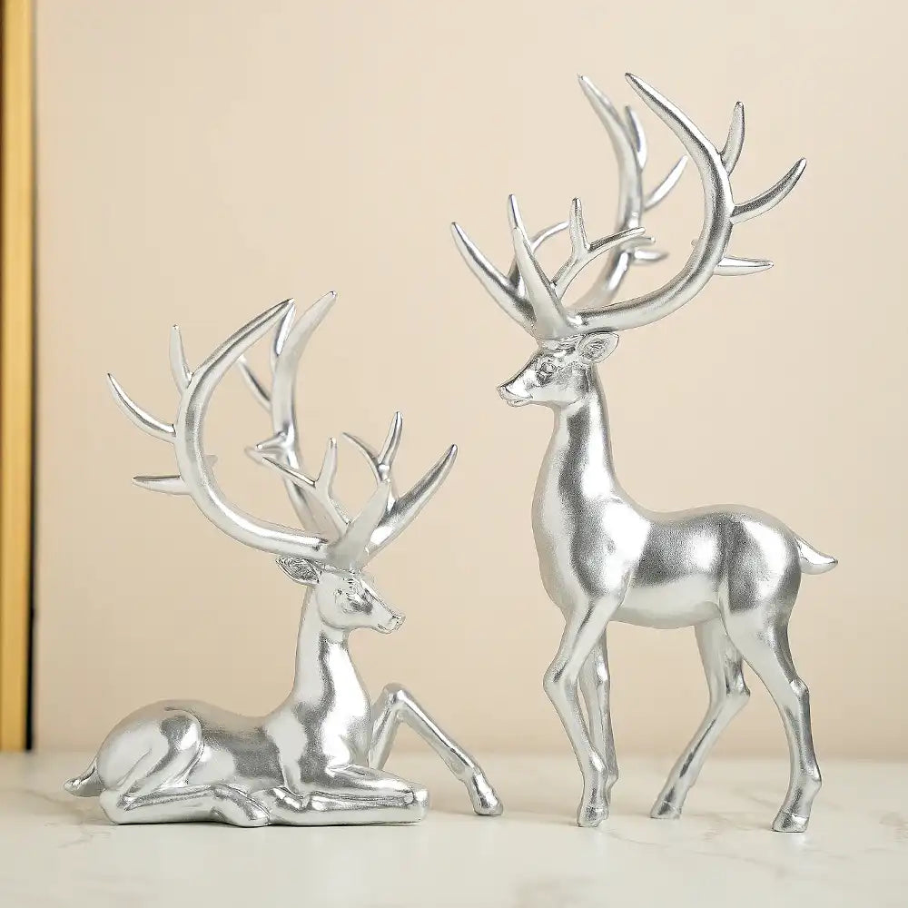 Two silver deer figurines on a beige background