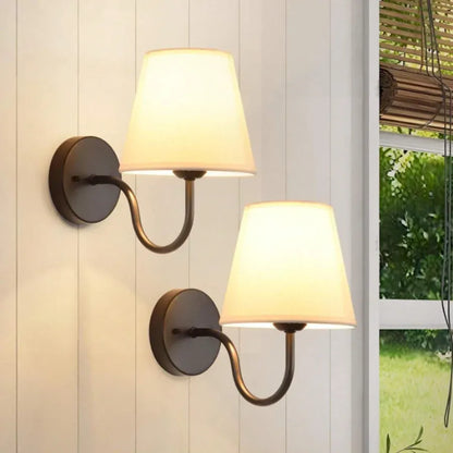Two wall-mounted lamps with white shades on a light-colored wall.