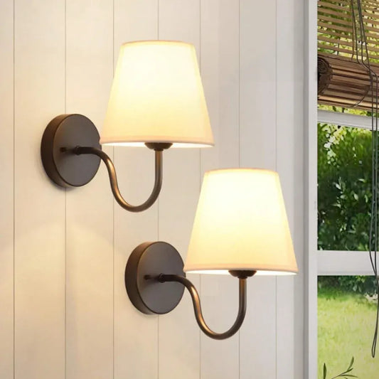 Two wall-mounted lamps with white shades on a light-colored wall.