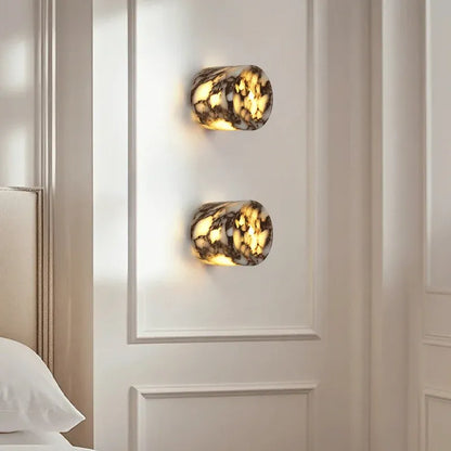 Two wall-mounted lights with a marble-like finish on a white paneled wall.