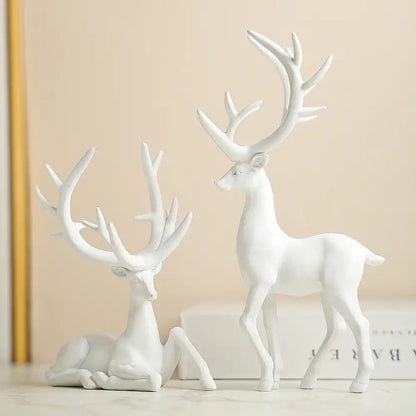 Two white deer figurines with large antlers on a beige background