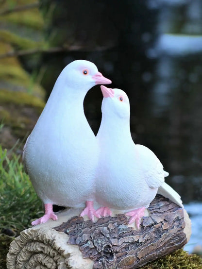 Two white doves sculptors standing on a wooden log with a blurred natural background