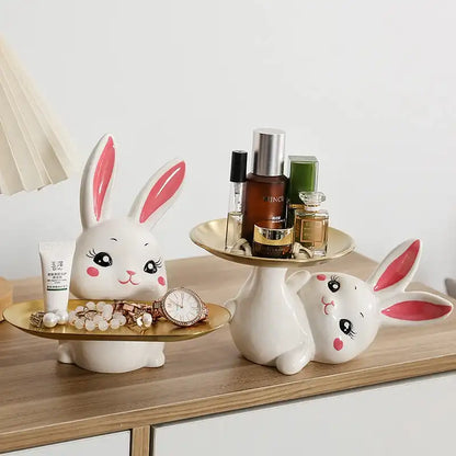 Two white rabbit-shaped stands with decorative items on a wooden surface.