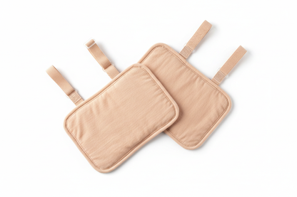 Pair of underarm sweat stopper pads flat lay showing skin-colored design, adjustable straps, and double cotton layer construction
