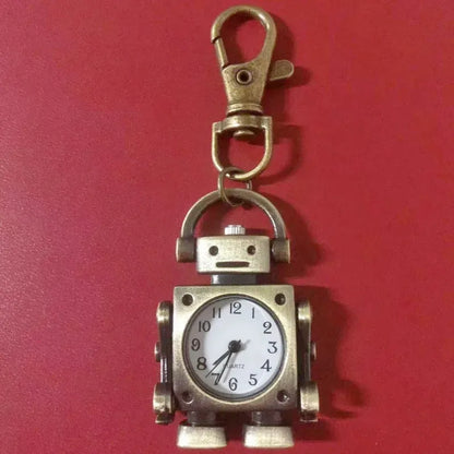 Bronze robot-shaped keychain with clock face on a red background