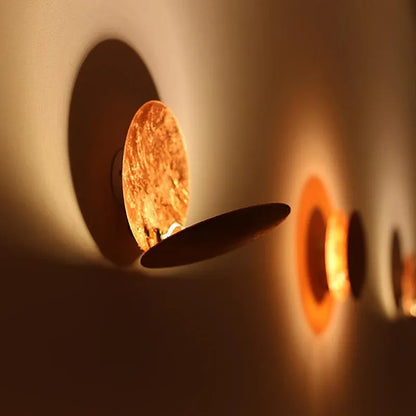 Wall-mounted light fixture casting a warm glow on a neutral background