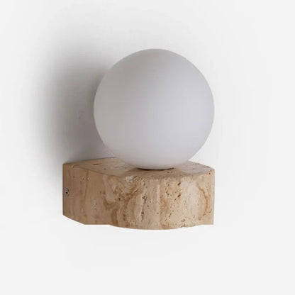 Wall-mounted light fixture with a spherical white bulb on a textured beige base against a white background