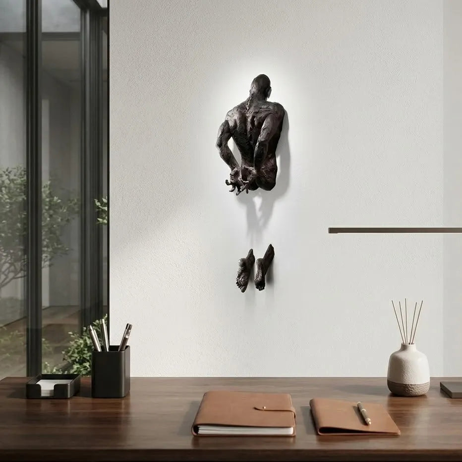 Wall-mounted sculpture of a man in a modern office setting with desk items.
