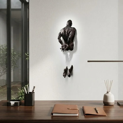 Wall-mounted sculpture of a man in a modern office setting with desk items.
