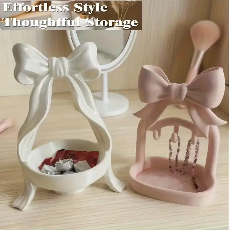 White and pink jewelry holders with bow designs on a wooden surface.