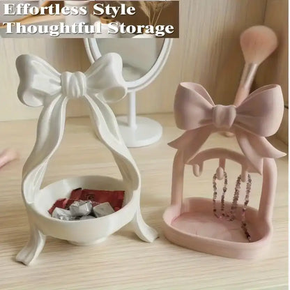 White and pink jewelry holders with bow designs on a wooden surface.