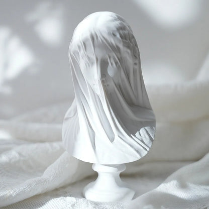 White marble statue with a draped cloth over its head on a textured white background