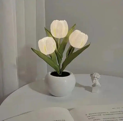 White tulips in a pot on a white surface with a light gray curtain background