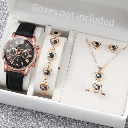 Rose gold watch and jewelry set with heart-shaped earrings and necklace on a gray surface.