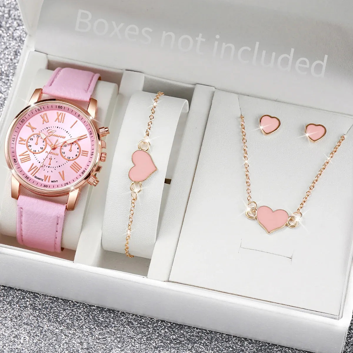 Pink watch and jewelry set with heart designs on a gray surface