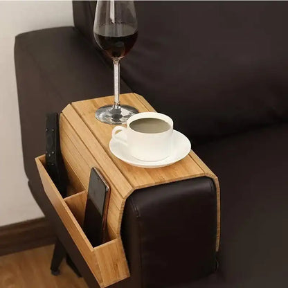Wooden side table with cup, saucer, and wine glass on a black sofa.