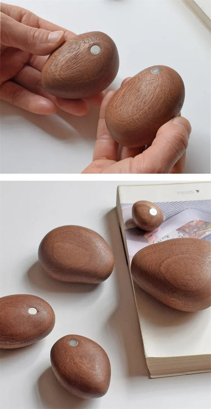 Wooden stones with holes held by a hand and placed on a white surface.