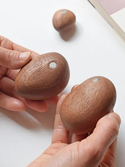 Wooden stress balls held in hands with a plain background