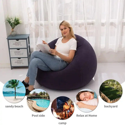 Woman sitting on a bean bag chair reading a book in a room with a window and nightstand.