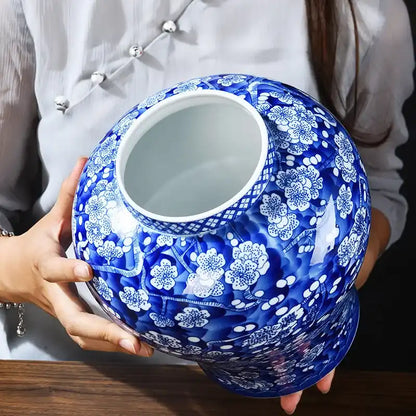 Person holding a blue and white ceramic vase with floral patterns