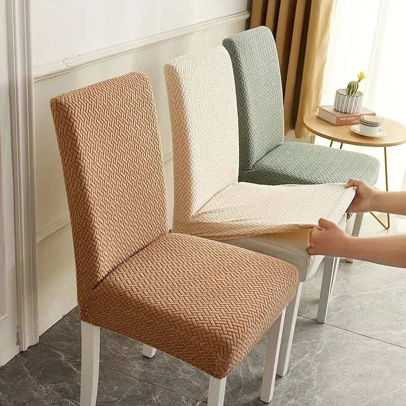 Person applying a chair cover to a brown chair in a room with a table and curtains.