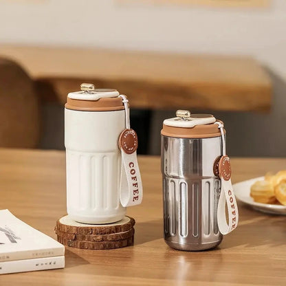 Two insulated coffee cups with wooden lids on a wooden table.