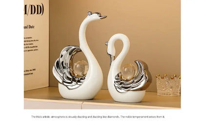 Two decorative swan figurines with silver and glass accents on a beige shelf.