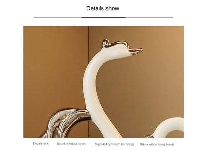 Two decorative swan figurines with silver and glass accents on a beige shelf.