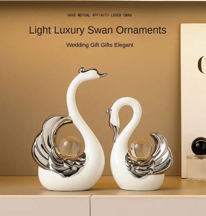 Two decorative swan figurines with silver and glass accents on a beige shelf.